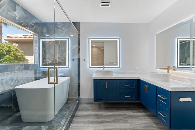 Primary bathroom with navy vanity and freestanding tub